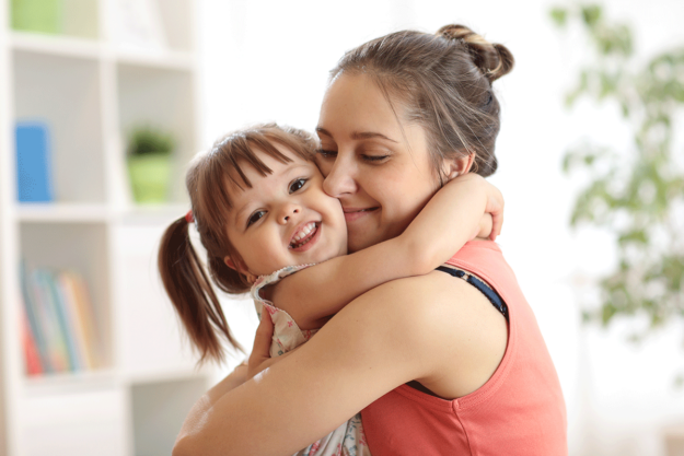 a mother hugs her toddler daughter