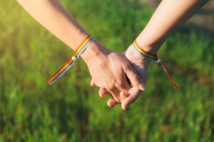 people holding hands in the grass with rainbow bracelets 